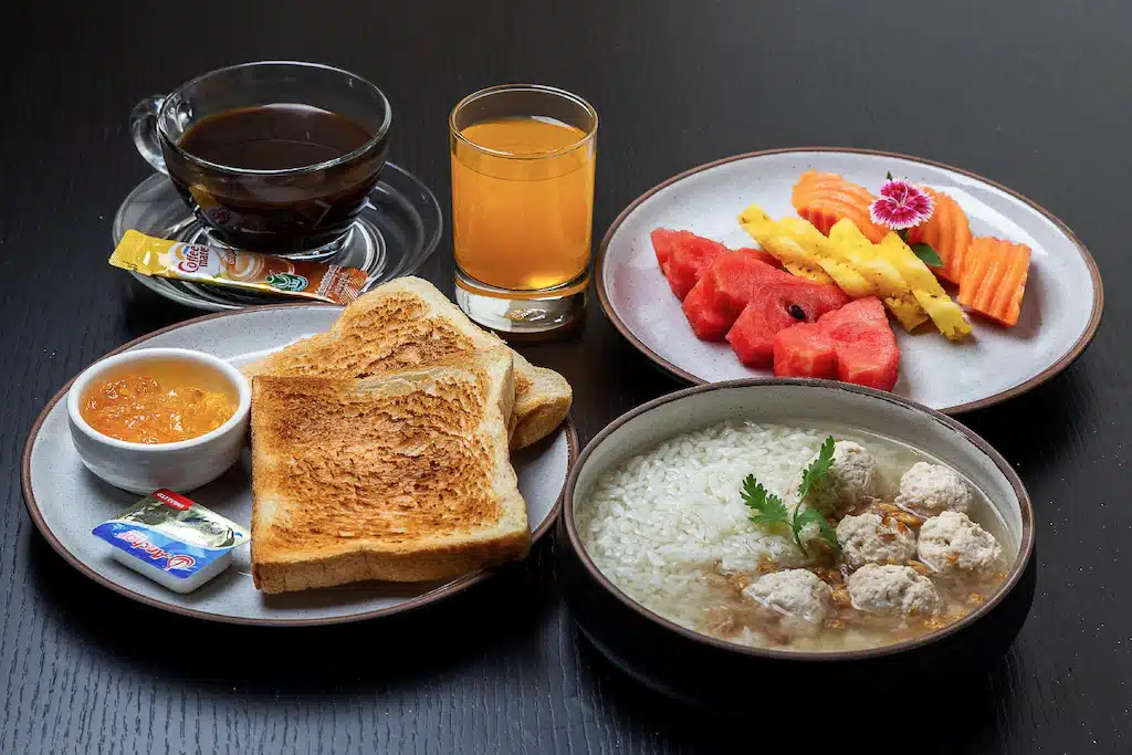 จานอาหารและกาแฟหนึ่งแก้วบนโต๊ะที่บ้านปทุมธานี ที่พักปทุมธานี