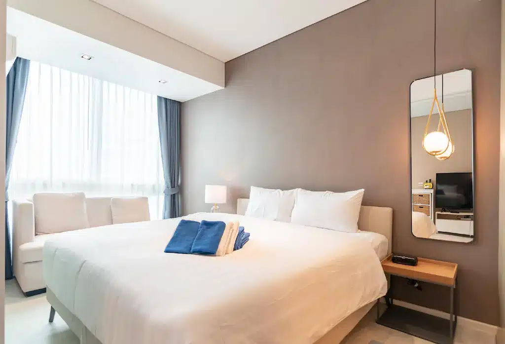 ห้องพักในโรงแรมที่มีเตียงสีขาวและผ้าเช็ดตัวสีฟ้า ตั้งอยู่ใกล้หาดจอมเทียน ที่พักหาดจอมเทียนติดทะเล