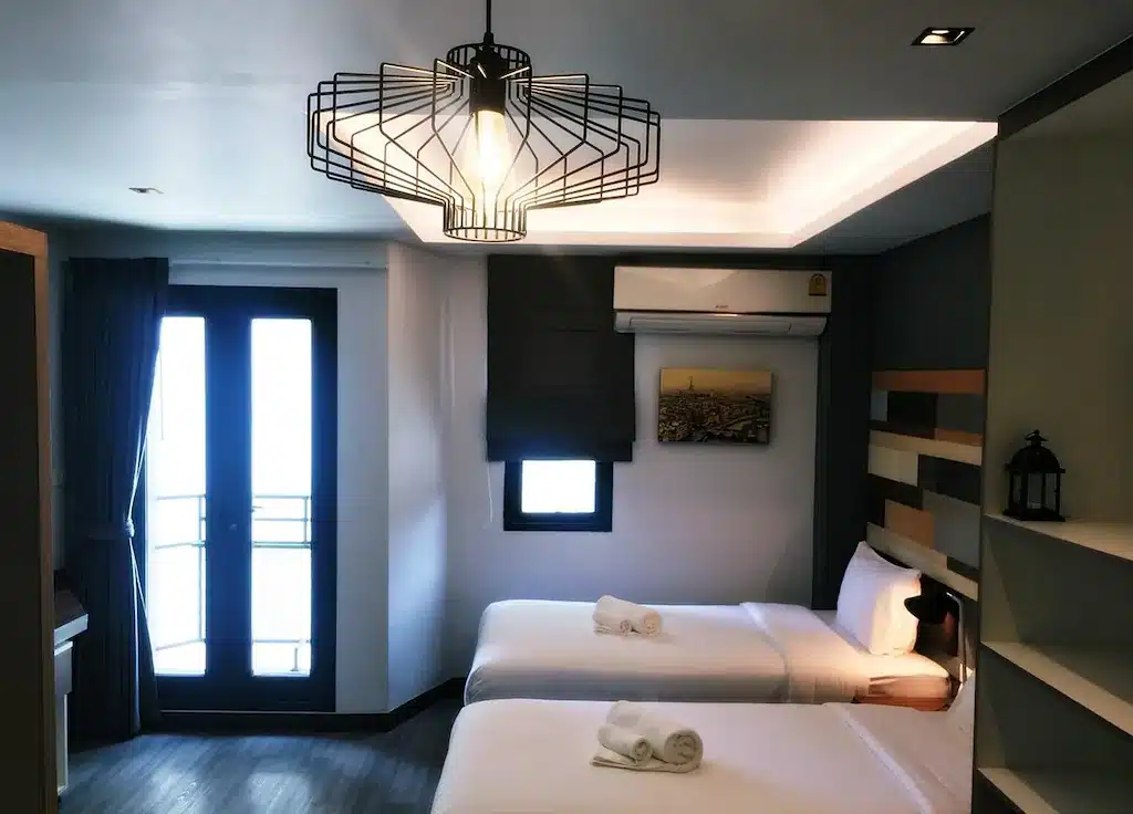 ห้องพักแสนสบายที่มีเตียง 2 เตียงและโคมไฟอยู่ในนั้น ที่พักปทุมธานี