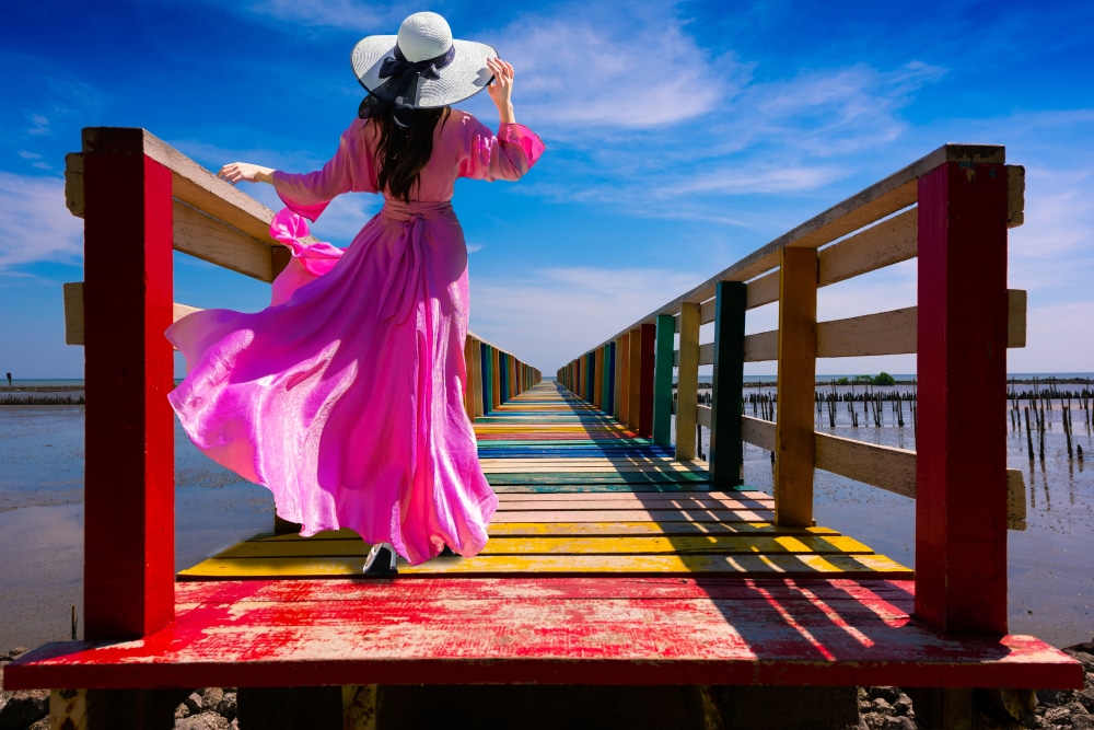 ผู้หญิงชุดสีชมพู เดินบนสะพานไม้ ที่ราชบุรีที่เที่ยว ที่เที่ยวสมุทรสาคร