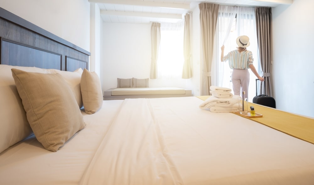 ผู้หญิงคนหนึ่งยืนอยู่หน้าเตียงในห้องพักของโรงแรมแห่งหนึ่งในพทุมตานี