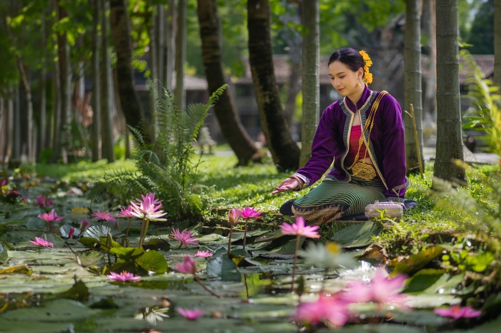 ผู้หญิงกำลังนั่งอยู่บนสระน้ำที่ล้อมรอบด้วย ดอยหลวงเชียงดาว  ดอกบัวที่สวยงามที่ดอยเชียงดาวประเทศไทย