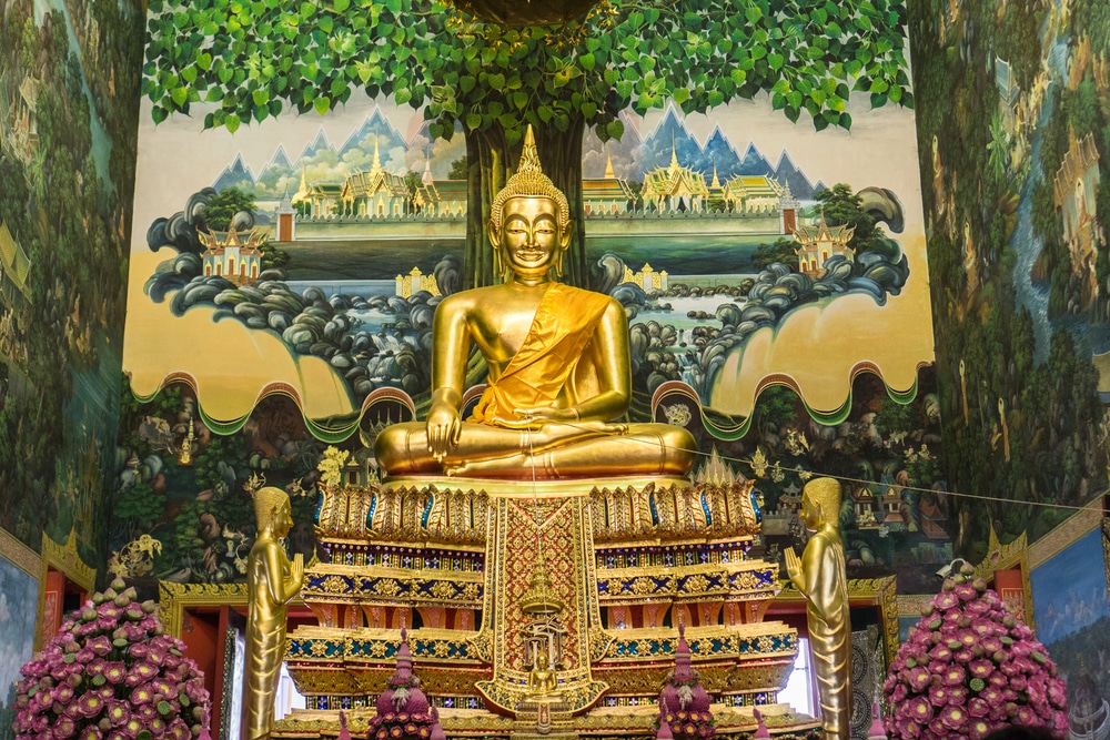 พระพุทธรูปทองคำประทับอยู่หน้าภาพวาดที่ วัดในนครปฐม