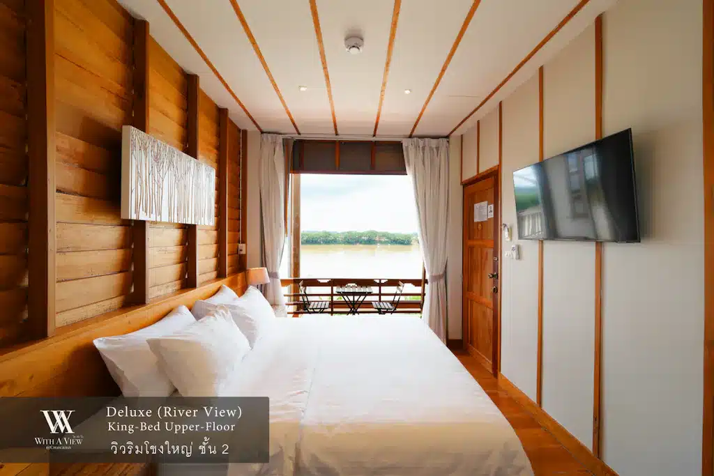 เตียงแสนสบายในห้องที่มีผนังไม้และทีวี เหมาะสำหรับนักเดินทางที่แสวงหาการพักผ่อนและความบันเทิง เที่ยวเชียงคาน