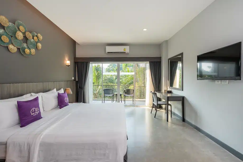 ห้องพักในโรงแรมที่มีเตียงขนาดใหญ่และหมอนสีม่วงในราชบุรีที่เที่ยว ที่พักเกาะช้าง