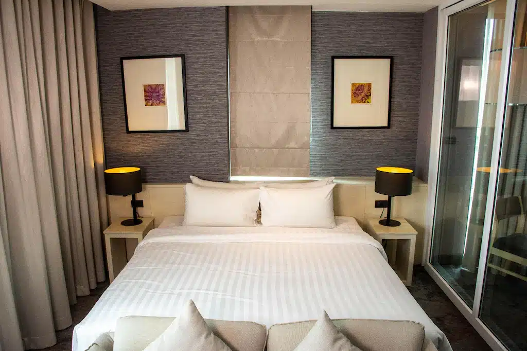 ห้องพักโรงแรมสมุทรปราการพร้อมเตียงและโต๊ะข้างเตียง ที่พักสมุทรปราการ