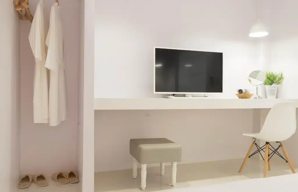 ห้องนอนสีขาวพร้อมทีวีและโต๊ะ ที่พักน่าน
