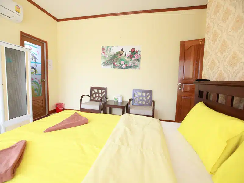เตียงนอนในห้องที่มีผ้าปูที่นอนสีเหลืองในราชบุรีที่เที่ยว ที่พักเกาะสีชัง