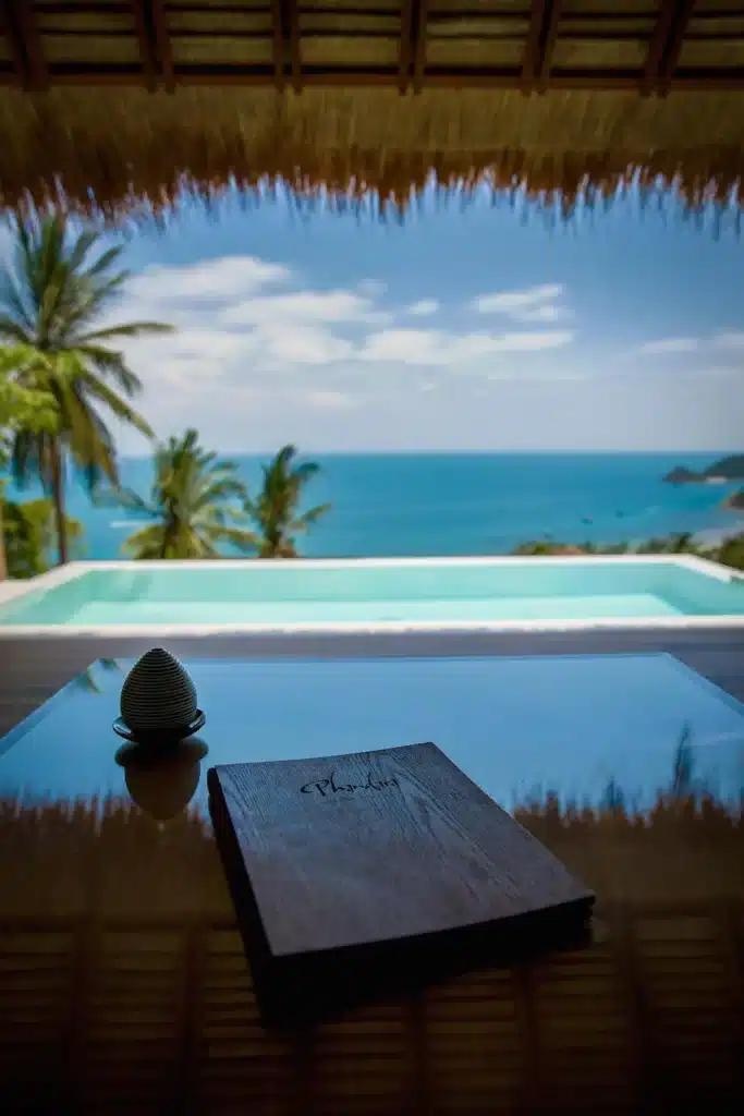 หนังสือบนโต๊ะริมสระน้ำ ที่พักเกาะเต่า พร้อมวิวทะเลในราชบุรี