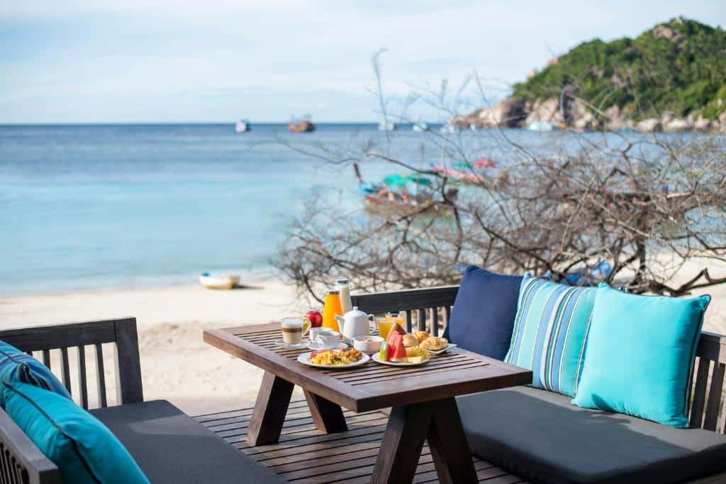 โต๊ะและเก้าอี้บนชายหาดพร้อมทิวทัศน์ของมหาสมุทรในเที่ยวราชบุรี ที่พักเกาะเต่า