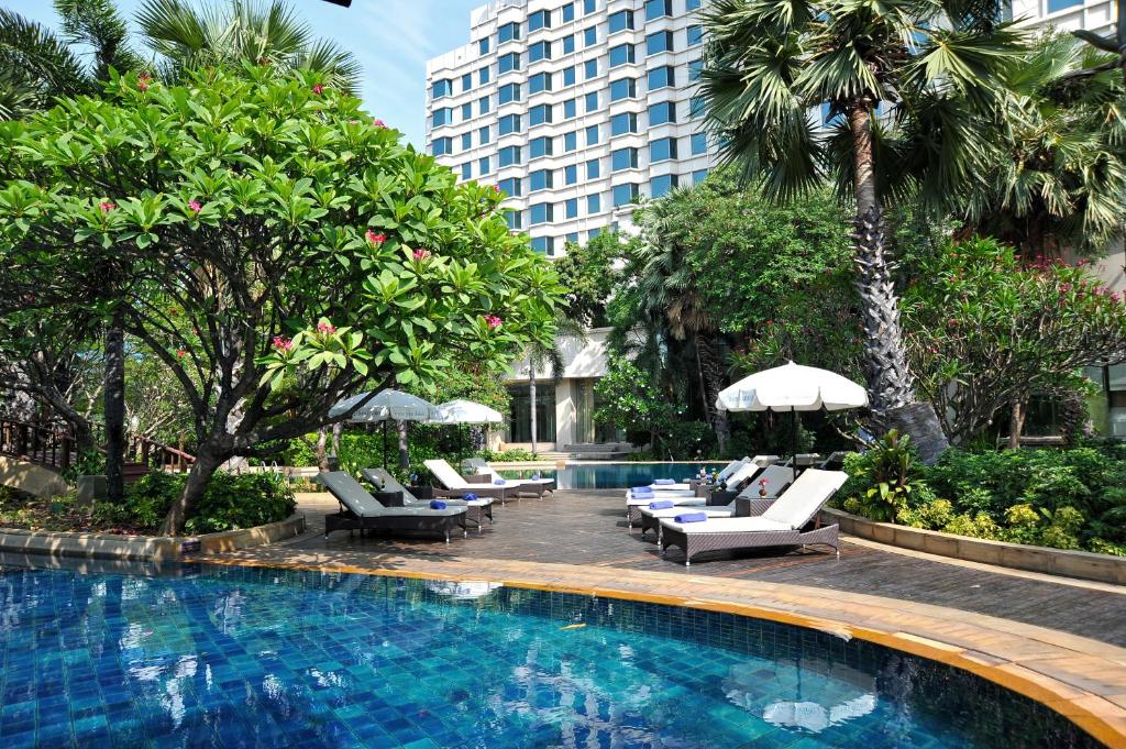 สระว่ายน้ำที่รายล้อมไปด้วยเก้าอี้นั่งเล่นและต้นไม้ในเมืองชัยบุรีอันงดงาม สถานที่ ที่พักกรุงเทพ ท่องเที่ยวยอดนิยมของจังหวัดราชบุรี