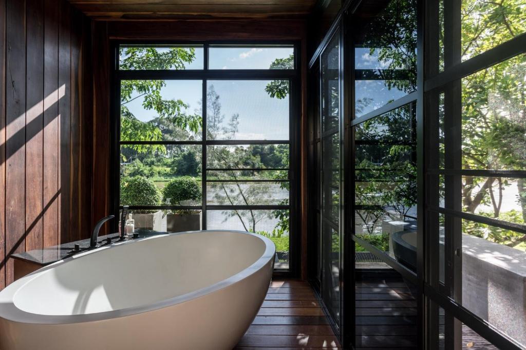 ห้องพักโรงแรมริมแม่น้ำในจังหวัดราชบุรี มีอ่างอาบน้ำและหน้าต่างบานใหญ่ ที่พักราชบุรีริมน้ำ