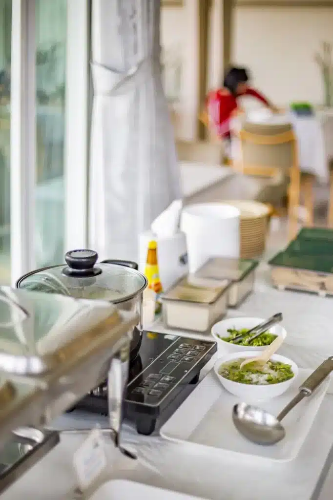 เคาน์เตอร์ครัวพร้อมเตา ชาม และอุปกรณ์ต่างๆ ในพื้นที่ท่องเที่ยวราชบุรี ที่พักสิงห์บุรี