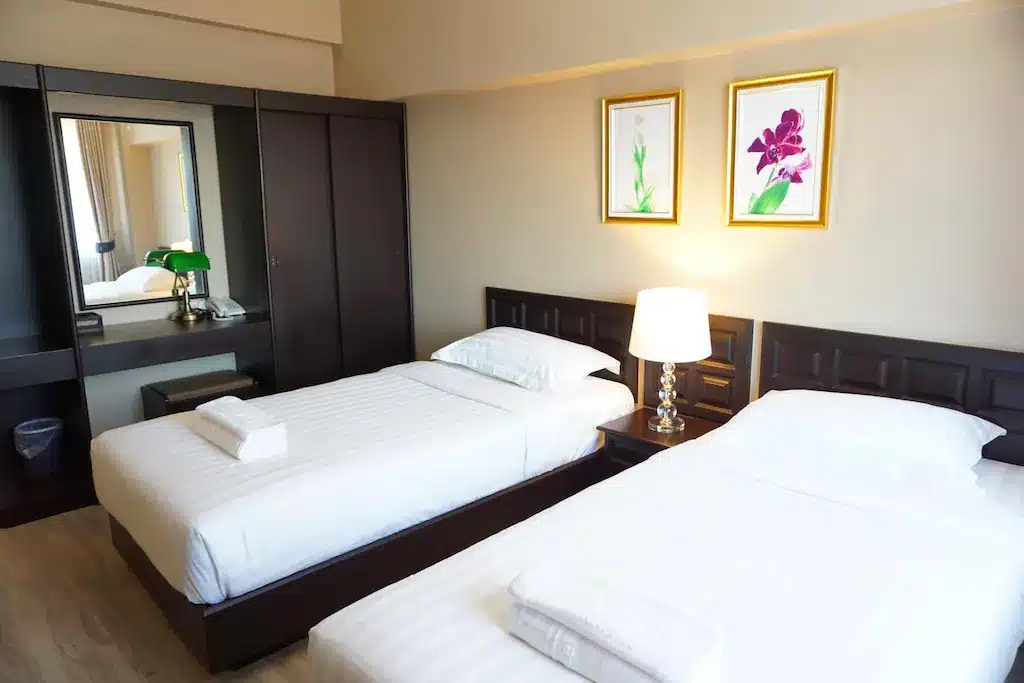 ห้องพักในโรงแรมที่มีสองเตียงและรูปภาพอันเงียบสงบบนผนัง ที่พักแพร่