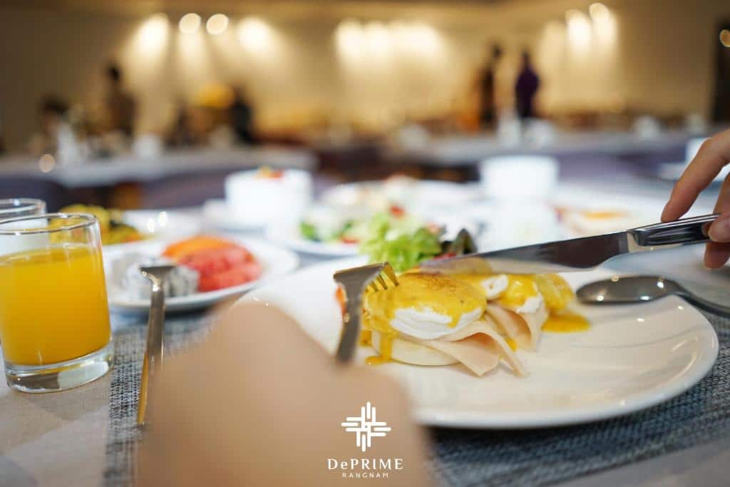 มีคนถือส้อมขณะรับประทานอาหารเช้าที่โต๊ะในอุทยานท่องเที่ยวราชบุรี โรงแรมในกรุงเทพ