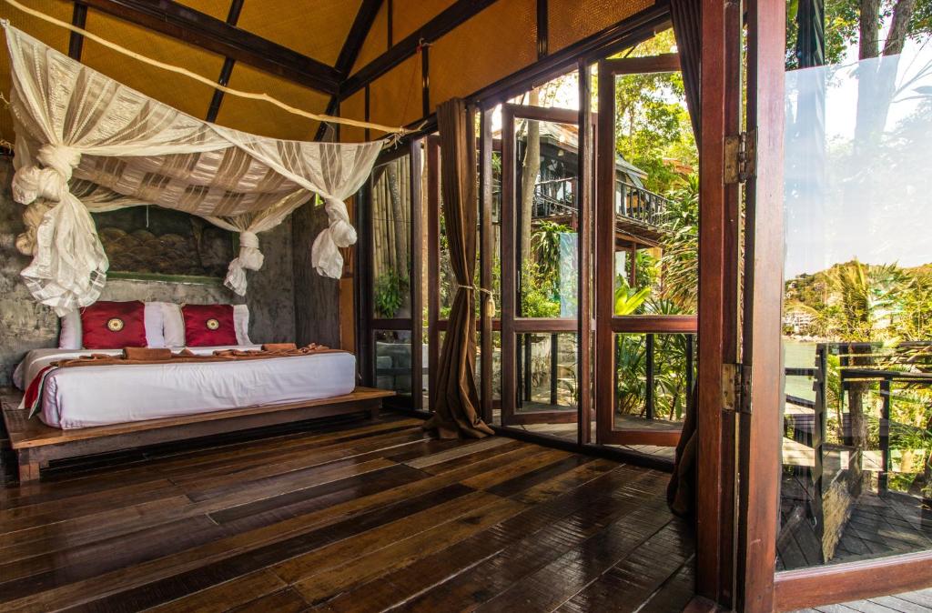 ห้องนอนบ้านต้นไม้พร้อมหลังคาเหนือเตียง เหมาะสำหรับการพักผ่อนในราชบุรี ที่พักเกาะเต่า