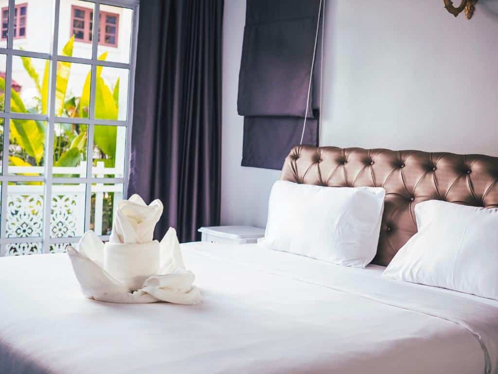 เตียงในห้องที่มีผ้าเช็ดตัวสีขาวและหน้าต่าง ที่พักน่าน