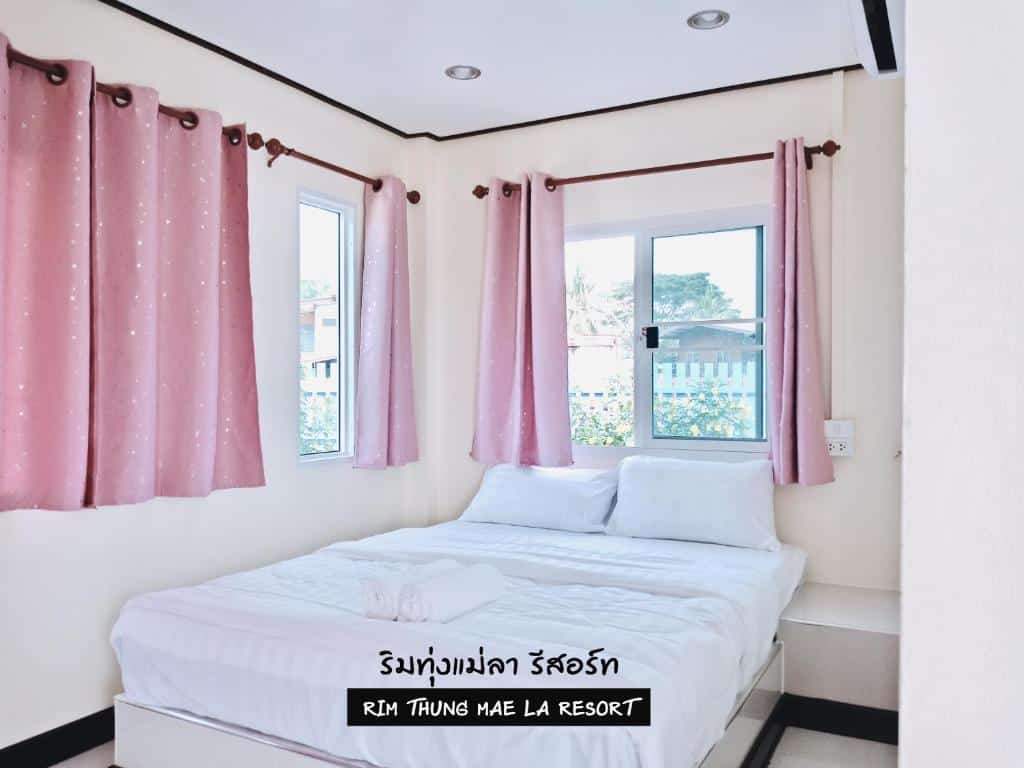 เตียงในห้องที่มีผ้าม่านสีชมพู หน้าต่าง และที่เที่ยวชัยนาท โรงแรมสิงห์บุรี