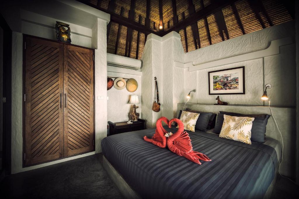 เตียงในห้องที่มีหัวเตียงไม้ เหมาะสำหรับนักเดินทางที่ต้องการสำรวจจังหวัดราชบุรีที่มีทิวทัศน์สวยงาม เกาะเต่าที่พัก