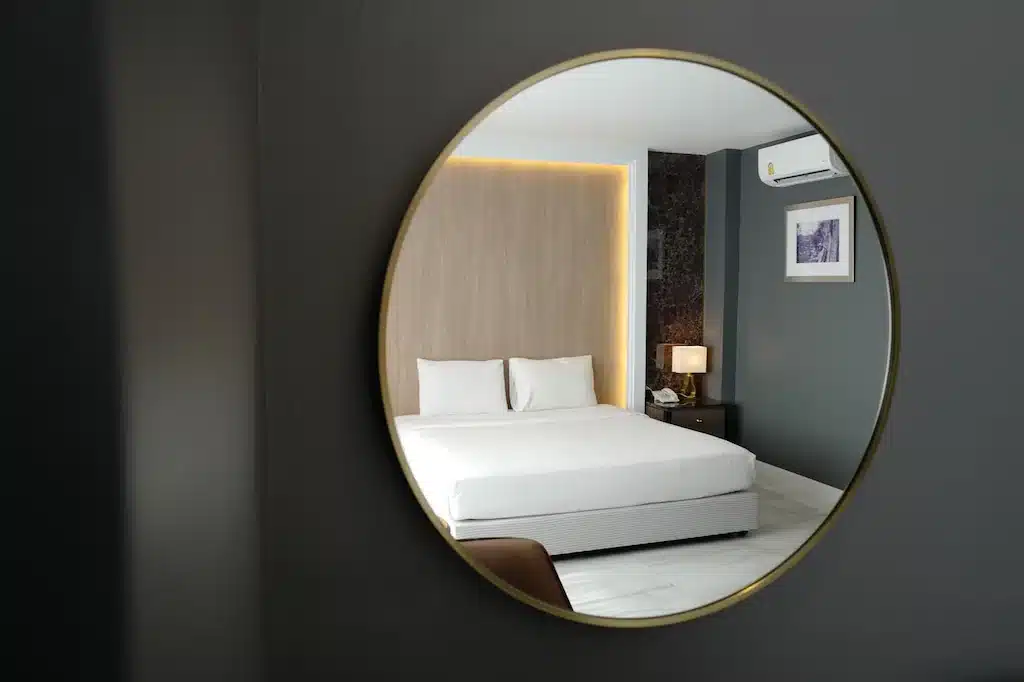 ห้องนอนที่มีกระจกทรงกลมเหนือเตียงในราชบุรีที่เที่ยว ที่พักสิงห์บุรี