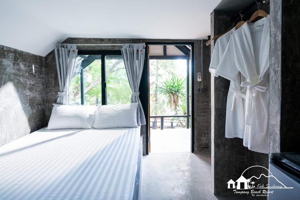ห้องที่มีเตียงและเสื้อคลุมแขวนอยู่บนผนังในจุดท่องเที่ยวราชบุรี ที่พักเกาะสีชัง