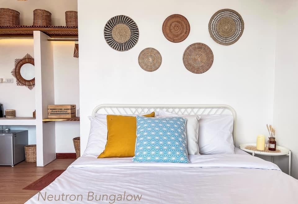 ห้องนอนพร้อมเตียงและโต๊ะข้างเตียงในราชบุรีที่เที่ยว ที่พักเกาะสีชัง
