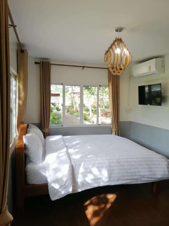 เตียงเรียบง่ายในห้องที่มีพื้นไม้และพัดลม ที่พักแพร่