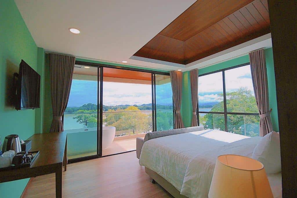 ห้องนอนผนังสีเขียวและระเบียงมองเห็นวิวทะเลสาบในราชบุรี ที่เที่ยวเชียงคาน