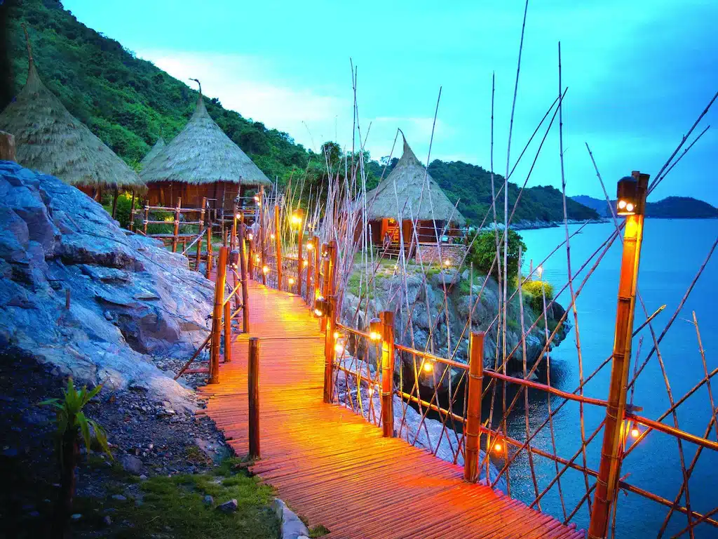 ทางเดินไม้อันงดงามที่นำไปสู่กระท่อมที่มีเสน่ห์บนชายหาดอันเงียบสงบของราชบุรีที่เที่ยว ที่พักเกาะสีชัง