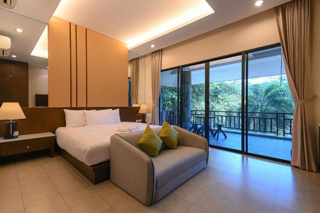 ห้องพักในโรงแรมพร้อมเตียงและระเบียงที่มองเห็นวิวธรรมชาติที่สวยงามของราชบุรี ที่พักราชบุรีริมน้ำ