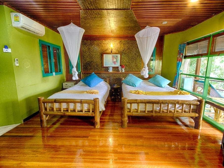 เตียง 2 เตียงในห้องที่มีผนังสีเขียวและพื้นไม้ เหมาะสำหรับนักท่องเที่ยวที่มาเยือนราชบุรี ที่พักเกาะเต่า