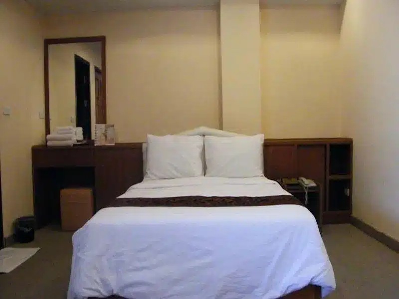 ห้องพักในโรงแรมพร้อมเตียงและโต๊ะ เหมาะสำหรับนักเดินทางที่สำรวจสถานที่ท่องเที่ยวที่สวยงามของราชบุรีและชัยนาท ที่พักสิงห์บุรี