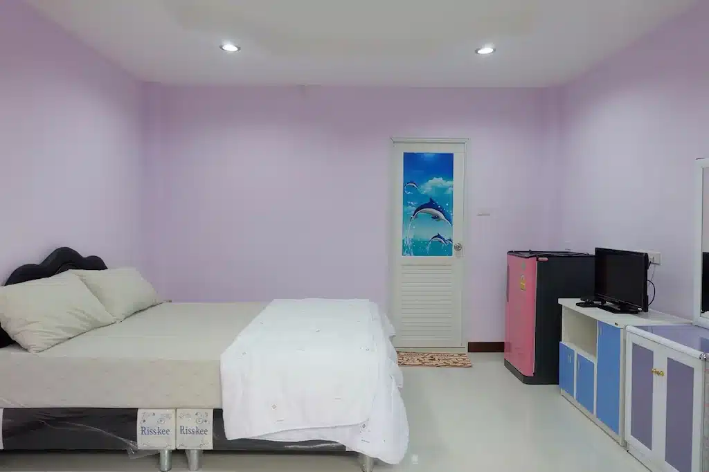 ห้องนอนเล็กผนังสีม่วงและเตียงนอนในราชบุรีที่เที่ยว ที่พักเกาะสีชัง