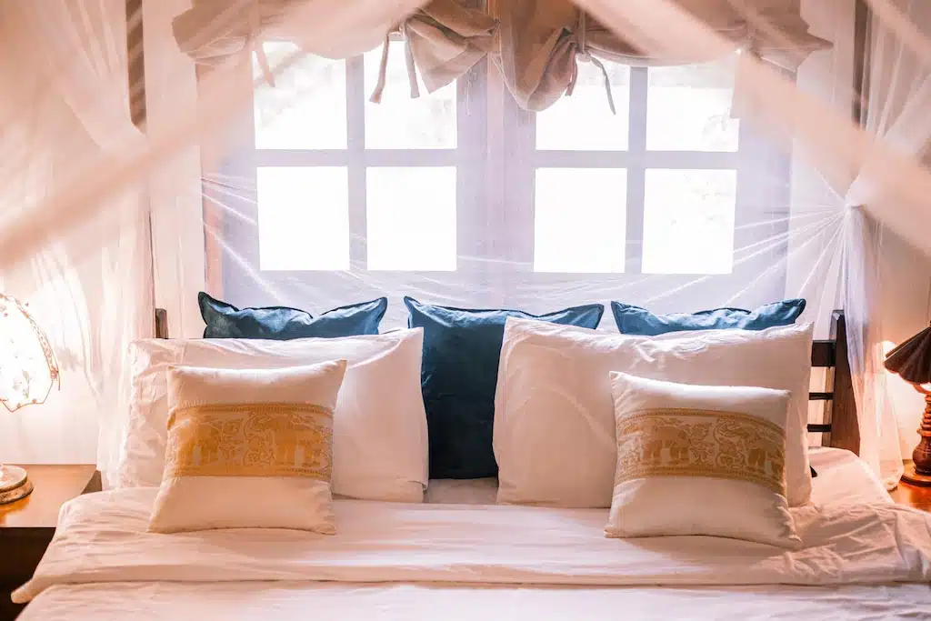 เตียงในห้องที่มีมุ้งเพื่อการเข้าพักอันเงียบสงบและปราศจากแมลง ที่พักริมน้ำราชบุรี
