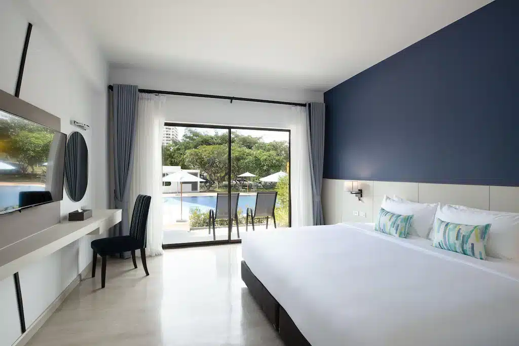 ห้องพักในโรงแรมที่มีผนังสีฟ้าและผ้าปูที่นอนสีขาว ที่เที่ยวชะอำ