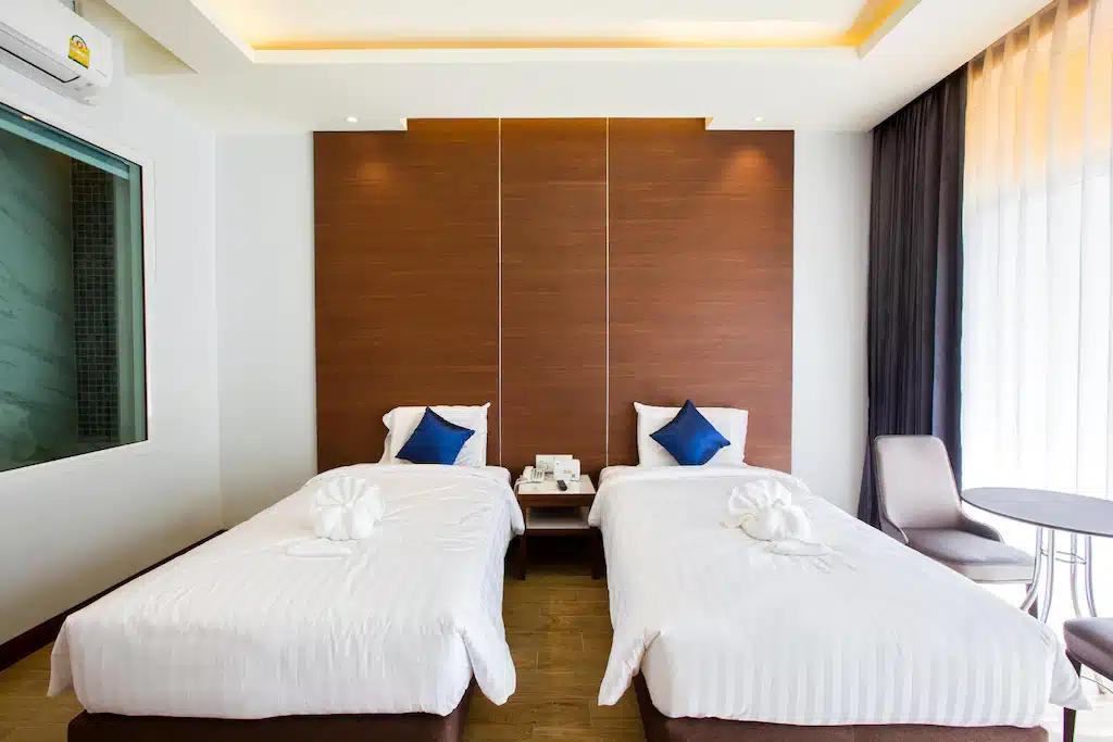 ห้องพักในโรงแรมที่มี 2 เตียงและหน้าต่าง ตั้งอยู่ในเมืองราชบุรีที่มีเสน่ห์ ขึ้นชื่อเรื่องสถานที่ท่องเที่ยวและสถานที่พักผ่อน ที่เที่ยวหาดใหญ่