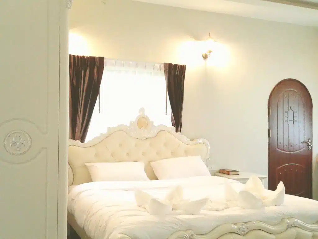 เตียงและตู้เสื้อผ้าสีขาวในห้องนอนริมแม่น้ำธรรมชาติในจังหวัดราชบุรี