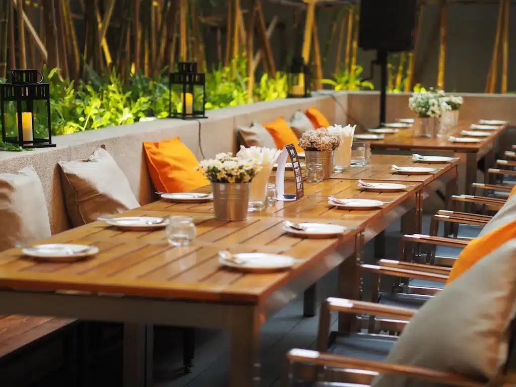 โต๊ะไม้ยาวพร้อมหมอนสีส้มใน ที่พักกทม ราชบุรีที่เที่ยว