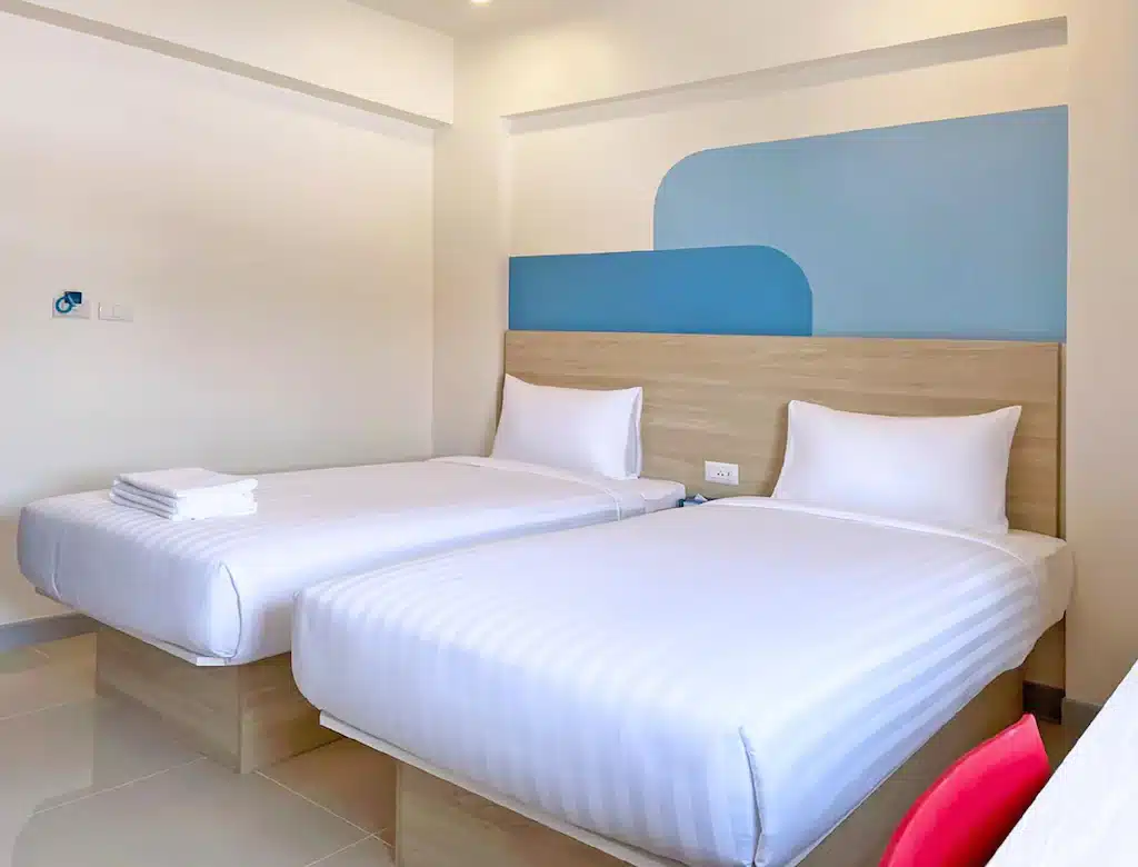 เตียงสองเตียงในห้องพักของโรงแรมที่มีผนังสีฟ้าและสีขาว มองเห็นทุ่งดอกกระเจียวชัยภูมิอันน่าทึ่ง ทุ่งดอกกระเจียวชัยภูมิ