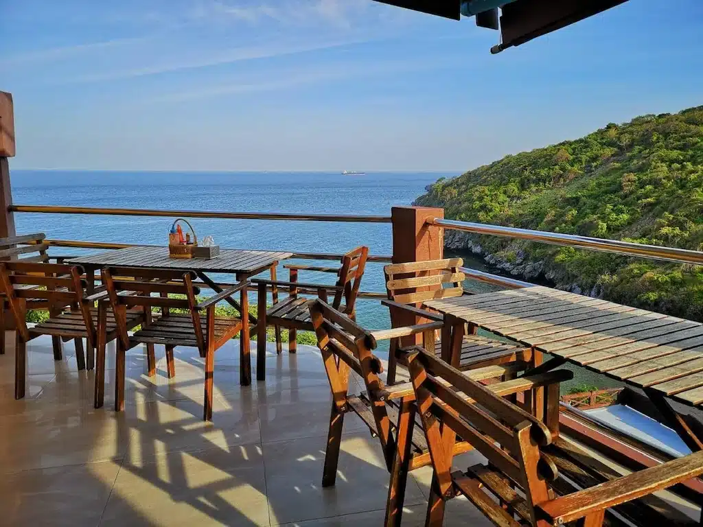 โต๊ะและเก้าอี้ไม้บนระเบียงที่มองเห็นวิว ที่พักเกาะสีชัง มหาสมุทรอันงดงามในราชบุรีที่เที่ยว