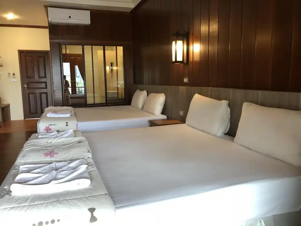 เตียงสองเตียงในห้องที่มีผนังไม้ ที่พักเกาะช้าง