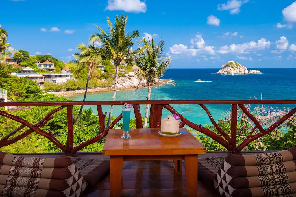 ระเบียงมองเห็นวิวทะเลพร้อมโต๊ะและเก้าอี้ในราชบุรี ที่พักเกาะเต่า