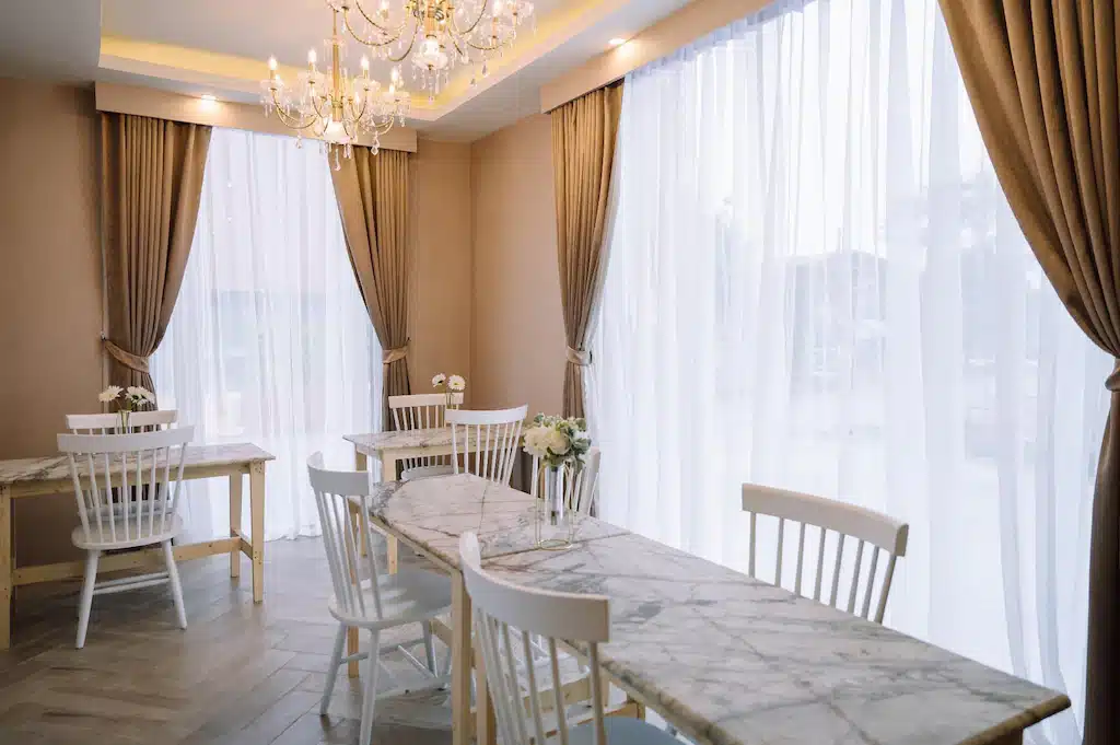 ห้องรับประทานอาหารพร้อมเก้าอี้สีขาวและโคมระย้าในบรรยากาศอ่าวนาง รีสอร์ทอุดรธานี