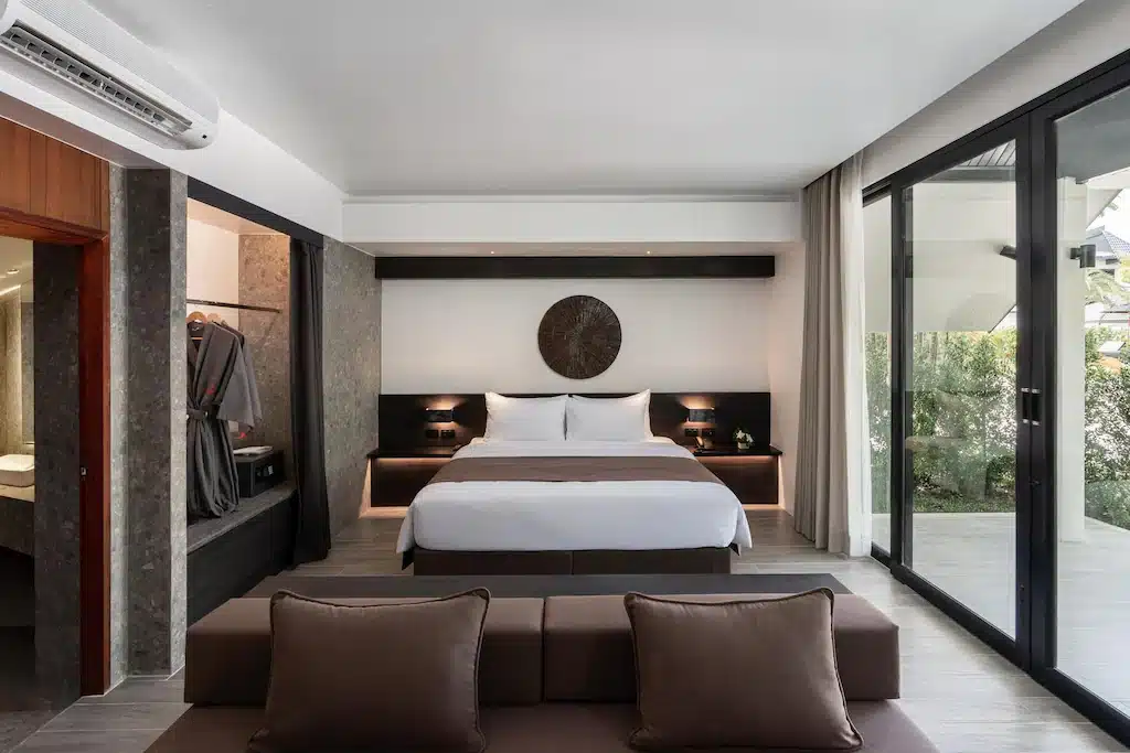 ห้องนอนที่มีประตูกระจกบานเลื่อนและเตียง ตั้งอยู่ในจังหวัดราชบุรีที่สวยงาม ที่พักเกาะช้าง