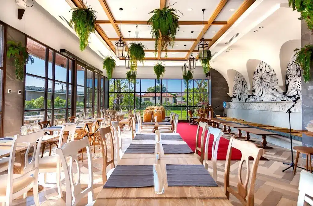 ร้านอาหารที่มีโต๊ะไม้และต้นไม้ห้อยลงมาจากเพดาน ตั้งอยู่ในสมุทรปราการ โรงแรมสมุทรปราการ