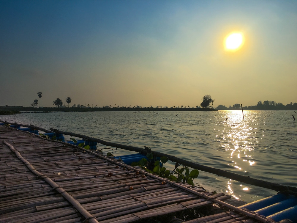 ท่าเทียบเรือไม้ริมทะเลสาบที่มีพระอาทิตย์ตกด้านหลังในราชบุรีที่เที่ยว ชัยนาทที่เที่ยว