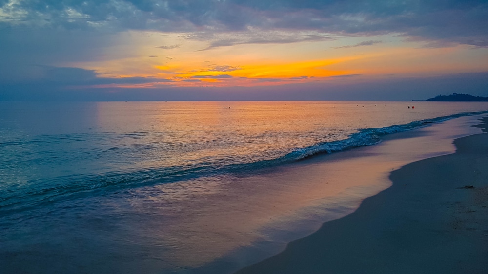 พระอาทิตย์ตกที่สวยงามบนชายหาดที่มีน้ำทะเลใสและหาดทรายสีทอง ที่เที่ยวหาดใหญ่