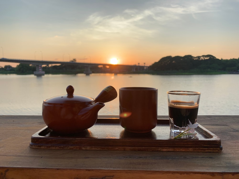 ชาและกาแฟสักแก้วบนถาดหน้าแม่น้ำ เหมาะสำหรับการพักผ่อนและเพลิดเพลินกับทิวทัศน์อันงดงามของเมืองชัยนาท