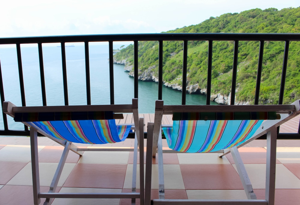 เก้าอี้สองตัวบนระเบียงที่มองเห็นทะเลที่เกาะสีชัง