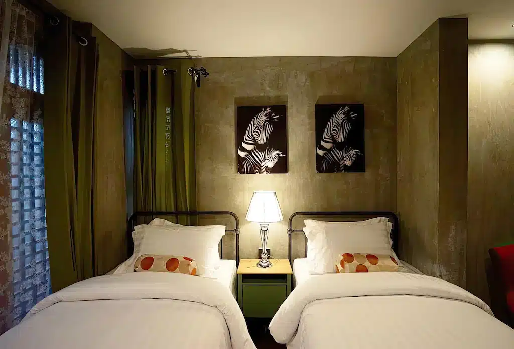 เตียงสองเตียงในห้องที่มีผนังสีเขียวและโคมไฟ เที่ยวสมุทรสงคราม